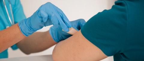 Nurse placing Band-aid on arm of person after vaccination