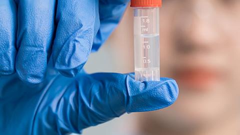 Scientist wearing gloves holding a vial