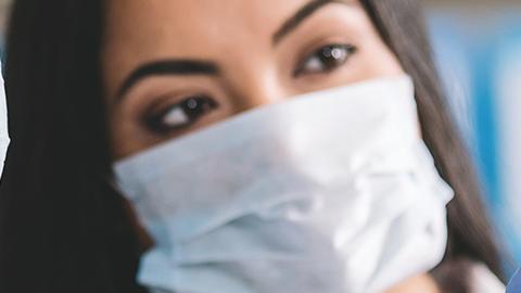 Two scientists wearing masks look at a vial