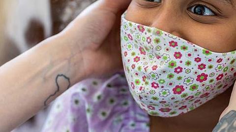 Woman putting face mask on a child