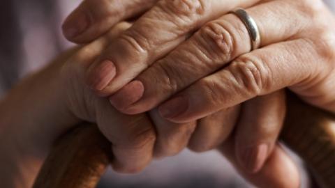 Hands folded on the top of a walking cane