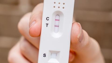 Hand holding positive COVID-19 test